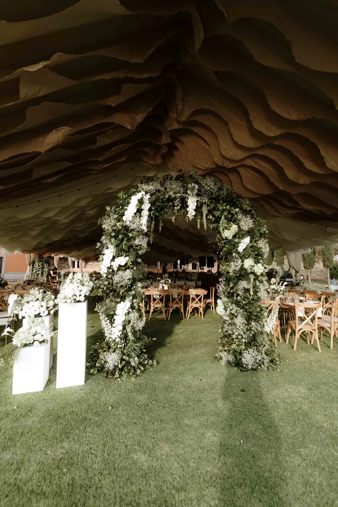 Arco de flores blancas y follaje bajo el toldo