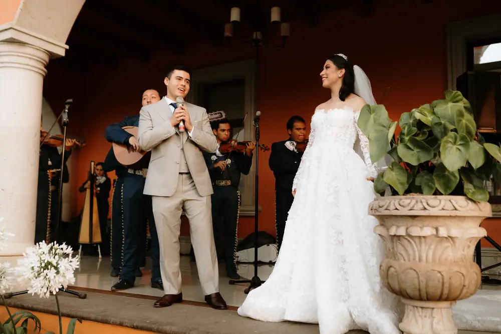 Los novios sonríen frente al mariachi en el portal de la hacienda