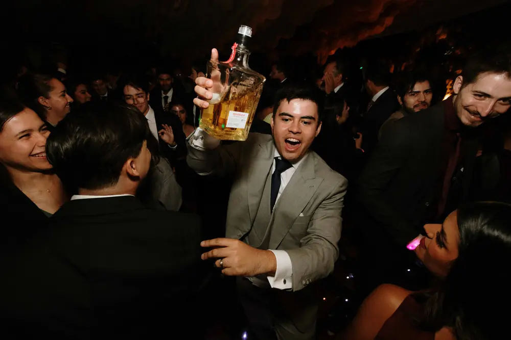 Invitado levanta una botella de tequila en plena fiesta