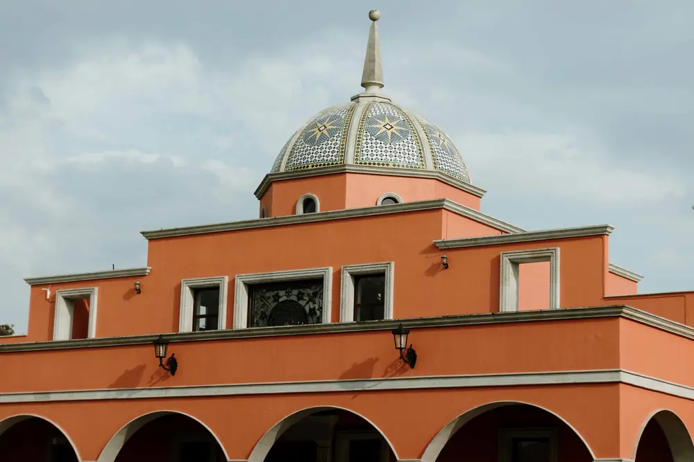 Cúpula de azulejo y fachada terracota de la hacienda bajo el cielo de la sierra